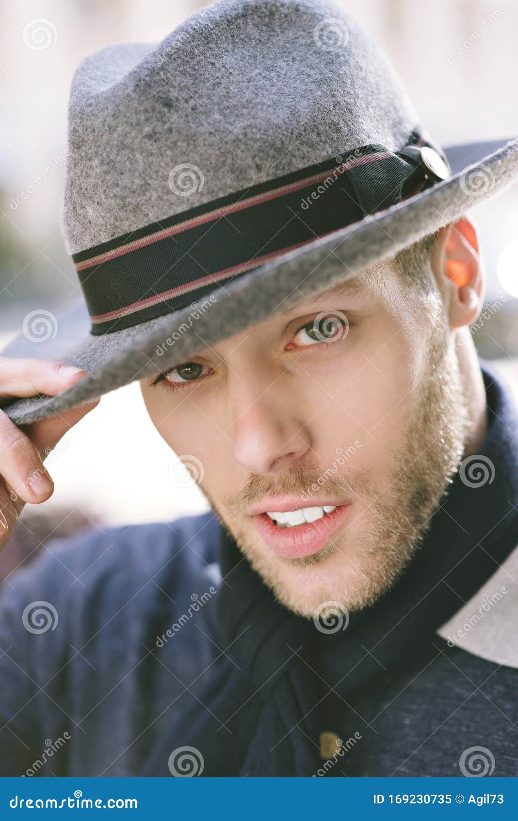 young-caucasian-man-tips-his-fedora-looking-camera-daytime-fashion-millennial-male-looks-placing-hand-hat-white-169230735.jpg