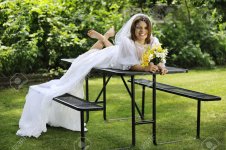29745867-A-beautiful-young-bride-happily-sprawled-across-a-picnic-table-barefoot-in-her-wedding-.jpg