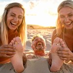 Firefly_a middle aged man, laughs, is buried in sand, has his feet tickled by two young women ...jpg